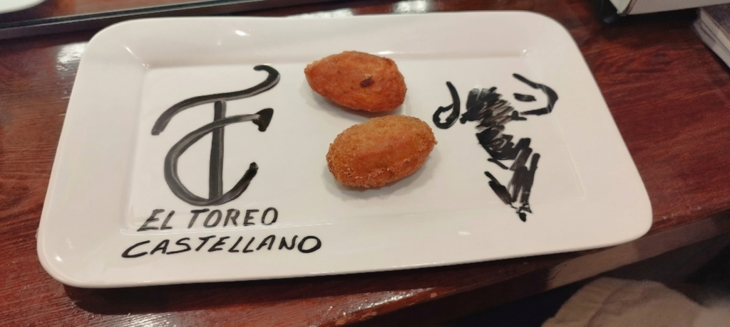 Plato con dos croquetas y el nombre de la revista "El Toreo Castellano" escrito como detalle de cortesía del Restaurante Valencia.